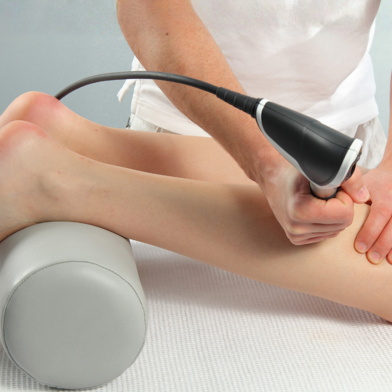 A physical therapist treats the lower leg with shockwave therapy to relieve muscle and tendon pain.