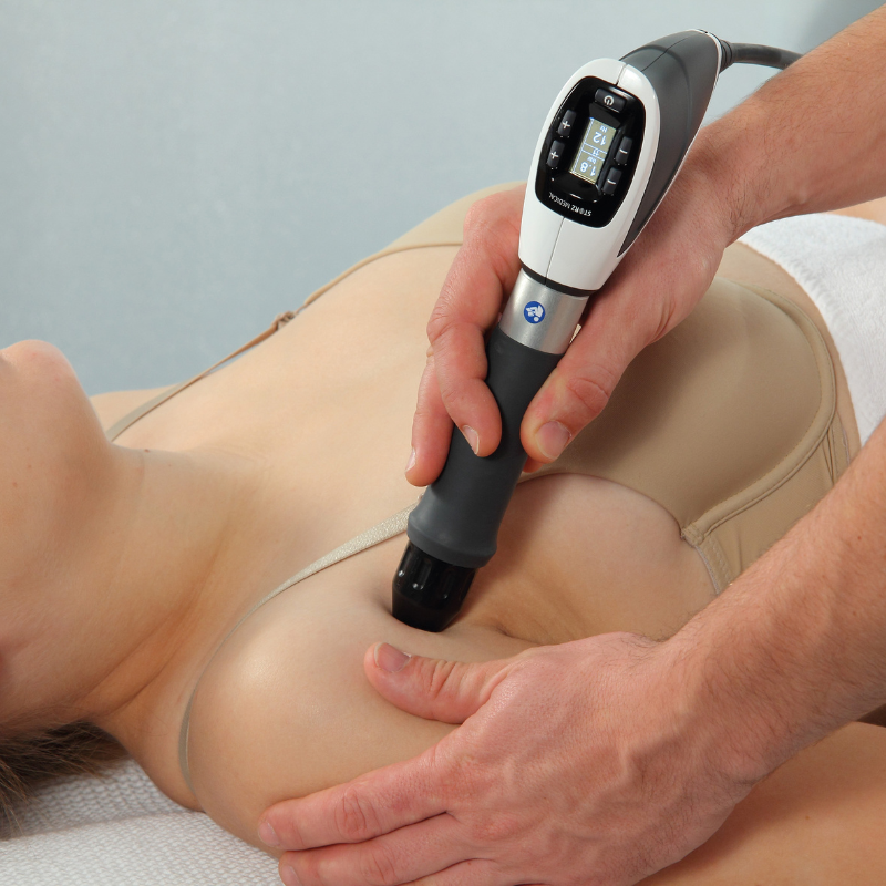 A physical therapist applies shockwave therapy to the shoulder to reduce pain and support tissue healing.