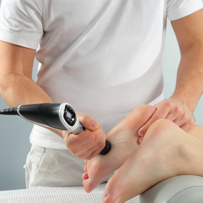 A therapist uses a shockwave therapy device on the patient’s foot to help treat chronic heel pain.