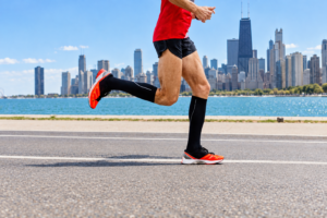 Runner wearing running shoes and black compression socks running along the Chicago lakefront.